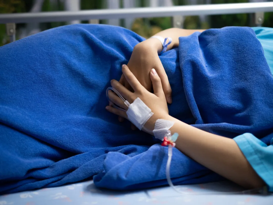 Persoon ligt zijwaarts met beide handen voor de buik.