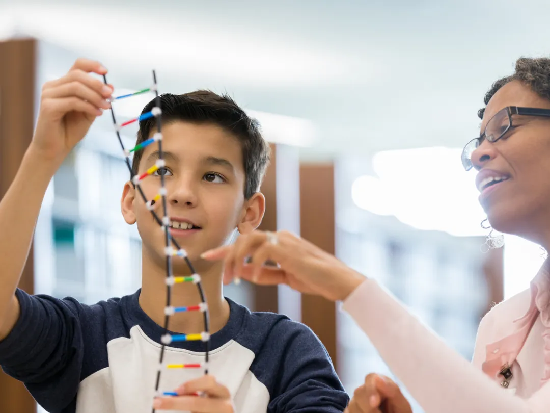 Jongen kijkt met vrouw naar DNA-helix model.