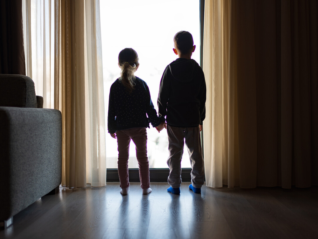 Twee kinderen die voor een raam staan