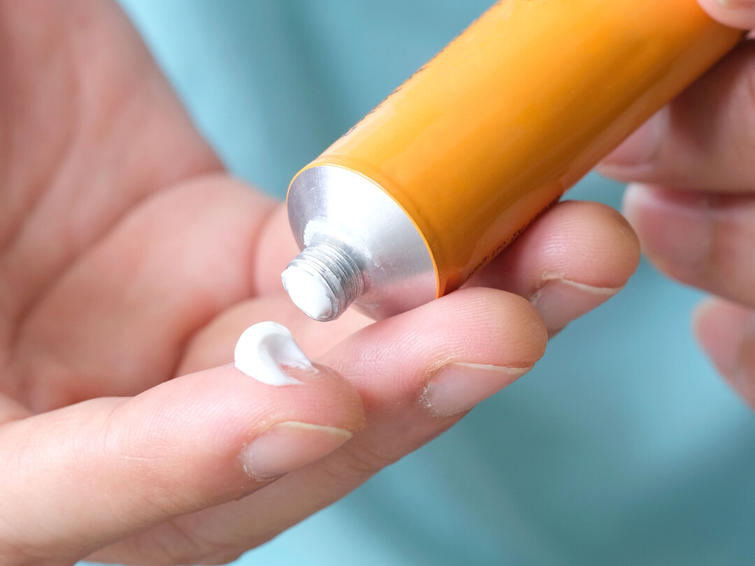 Hand met crème uit een tube