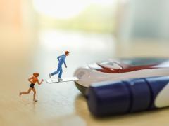 Een glucosemeter en insulinespuit liggen naast elkaar. Twee miniatuurfiguurtjes van hardlopers staan erbij.