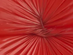 Een knoop in rood, latexachtig materiaal.