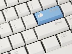 Close-up van een wit toetsenbord. Op de blauwe enter-toets staat het symbool van een omhooggestoken duim.