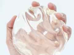 Een hand houdt een siliconen borstimplantaat vast.