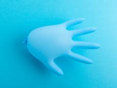 Een blauwe, opgeblazen rubberen handschoen tegen een blauwe achtergrond.