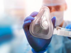 Een arts houdt een beademingsmasker in zijn handen.