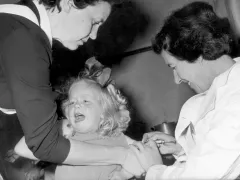 Zwart-wit foto van een kind dat een vaccinatie krijgt toegediend.