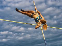 Een polsstokspringer tegen een bewolkte lucht.