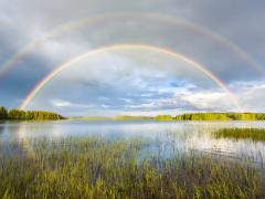 Een dubbele regenboog boven een meer.