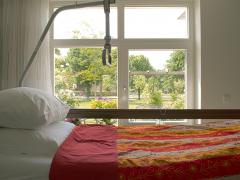 Een ziekenhuisbed naast een raam met uitzicht op een groene omgeving.