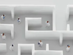 Meerdere mensen in een wit doolhof van bovenaf gezien.