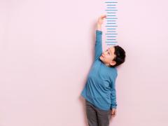 Jongetje dat langs meetlat staat en graag veel groter zou willen zijn