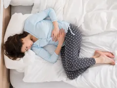 Vrouw op bed met buikpijn