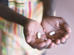 Handen van een zwarte vrouw met tabletten erin