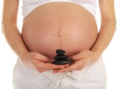 Vrouw met stenen in de hand voor zwangere buik