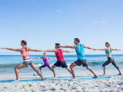 Mensen die yoga beoefenen op het strand