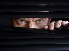 Een man die tussen lamellen doorkijkt