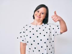 Vrouw met downsyndroom die duim omhoog houdt