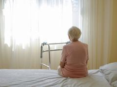 Oude vrouw op ziekenhuisbed met rollator voor zich