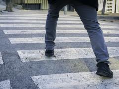 Iemand die een grote stap op een zebrapad neemt