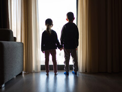 Twee kinderen die voor een raam staan