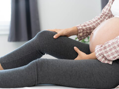 Zwangere vrouw die haar been vasthoudt