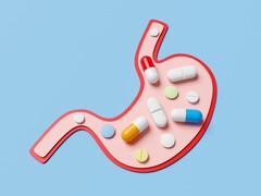 Een illustratie van een maag op een blauwe achtergrond, gevuld met verschillende soorten kleurrijke pillen