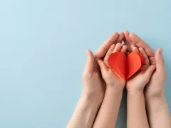 Volwassen handen met daarin kinderhanden met een hart