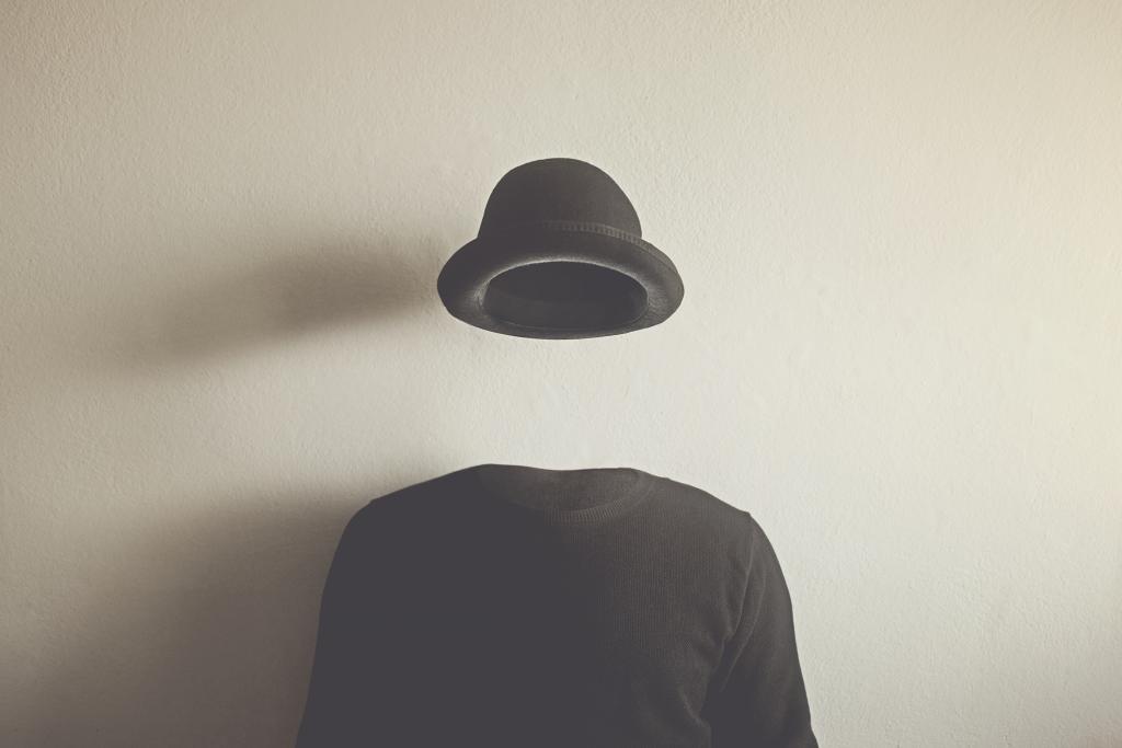 Een onzichtbaar persoon draagt een zwarte trui en een zwarte hoed.