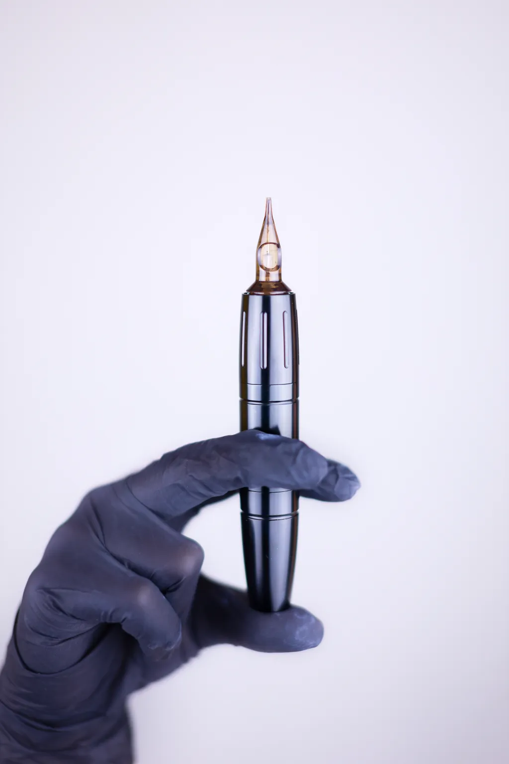 Een hand houdt een tattoomachine vast.