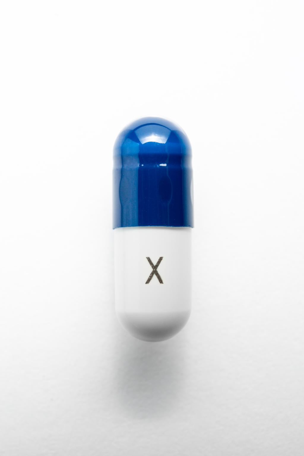 Blauwwitte capsule met een X op de onderkant geschreven.