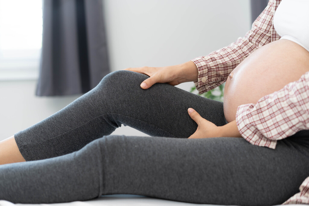 Zwangere vrouw die haar been vasthoudt